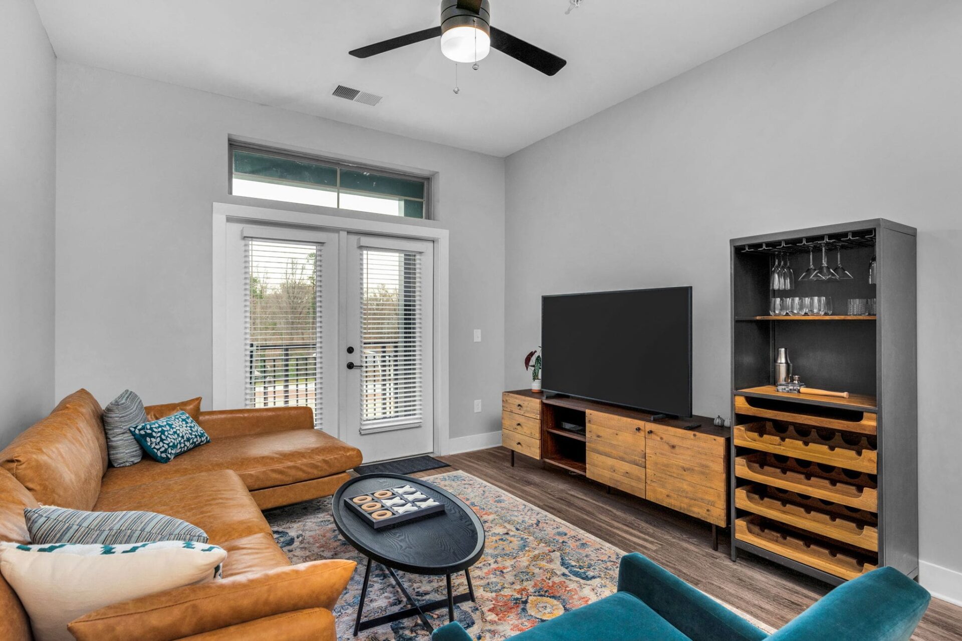 8-web-or-mls-2022_01_28 12_22_03-min A small, rustic-style living room with white walls, a light brown leather sectional, and wooden furniture.